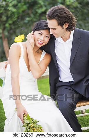 Stock Photo - Newlywed couple sitting together at wedding. Fotosearch