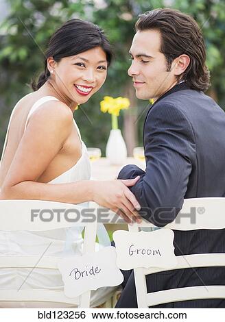 Newlywed couple sitting together at wedding reception View Large Photo Image Stock Photograph - Newlywed couple sitting together at wedding reception. Fotosearch