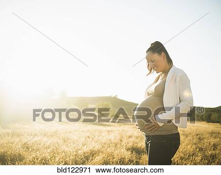 Pregnant Hispanic mother holding stomach in rural field View Large Photo Image Stock Image - Pregnant Hispanic mother holding stomach in rural field. Fotosearch