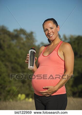 Pregnant Hispanic woman drinking water outdoors View Large Photo Image Stock Photo - Pregnant Hispanic woman drinking water outdoors. Fotosearch