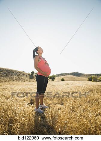 Pregnant Hispanic woman holding her belly in rural field View Large Photo Image Stock Image - Pregnant Hispanic woman holding her belly in rural field. Fotosearch