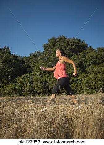 Stock Photo - Pregnant Hispanic woman walking outdoors. Fotosearch