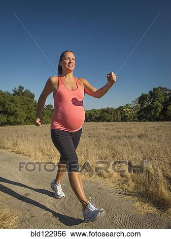 Stock Photograph - Pregnant Hispanic woman walking outdoors. Fotosearch