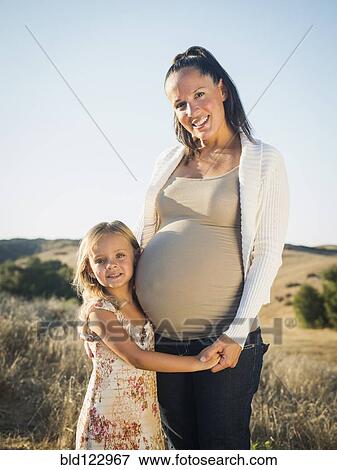 Stock Photo - Pregnant mother and daughter in rural field. Fotosearch