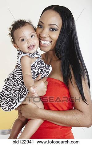 Smiling mother holding baby girl View Large Photo Image Stock Image - Smiling mother holding baby girl. Fotosearch