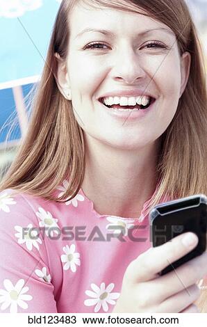 Smiling woman holding cell phone View Large Photo Image Stock Image - Smiling woman holding cell phone. Fotosearch
