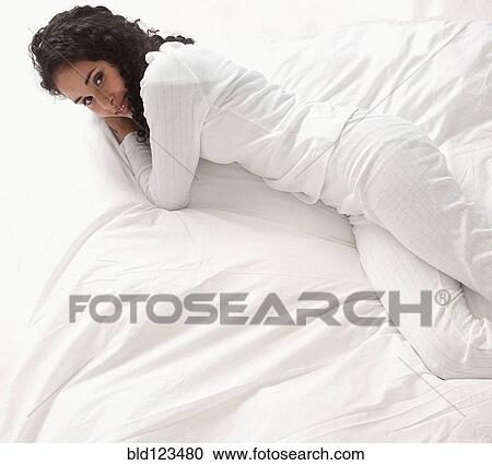 Stock Image - Smiling woman laying on bed. Fotosearch
