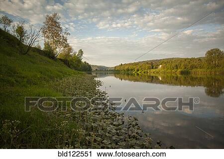 Stock Image - Still river in rural landscape. Fotosearch
