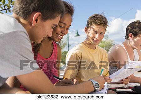 Teenagers doing homework together outdoors View Large Photo Image Stock Image - Teenagers doing homework together outdoors. Fotosearch