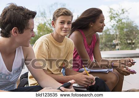 Teenagers doing homework together outdoors View Large Photo Image Stock Photography - Teenagers doing homework together outdoors. Fotosearch