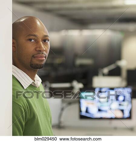 Stock Image - African American businessman standing in office. Fotosearch