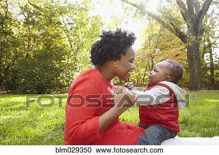 Stock Image - Black mother and toddler son playing in park. Fotosearch