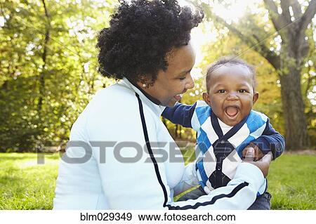 Black mother and toddler son playing in park View Large Photo Image Stock Photo - Black mother and toddler son playing in park. Fotosearch