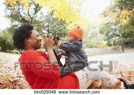 Black mother taking pictures of toddler son in park View Large Photo Image Stock Photo - Black mother taking pictures of toddler son in park. Fotosearch