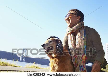 Stock Image - Black woman and dog relaxing in park. Fotosearch