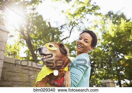Black woman carrying costumed dog in park View Large Photo Image Stock Image - Black woman carrying costumed dog in park. Fotosearch