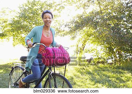 Stock Photograph - Black woman riding bicycle outdoors. Fotosearch