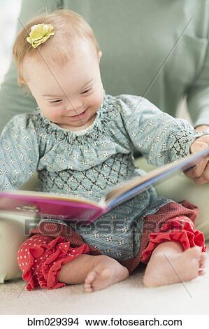 Caucasian baby girl with Down Syndrome reading View Large Photo Image Picture - Caucasian baby girl with Down Syndrome reading. Fotosearch