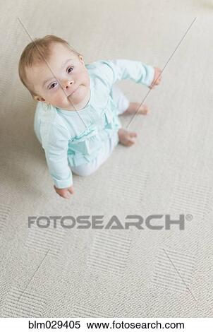 Stock Photography - Caucasian baby girl with Down Syndrome sitting on floor. Fotosearch