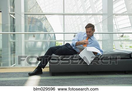 Caucasian businessman reading in lobby area View Large Photo Image Stock Photograph - Caucasian businessman reading in lobby area. Fotosearch