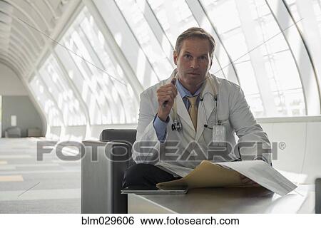 Caucasian doctor reading in lobby area View Large Photo Image Stock Photograph - Caucasian doctor reading in lobby area. Fotosearch