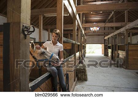 Caucasian girl petting horse in stable View Large Photo Image Stock Photograph - Caucasian girl petting horse in stable. Fotosearch
