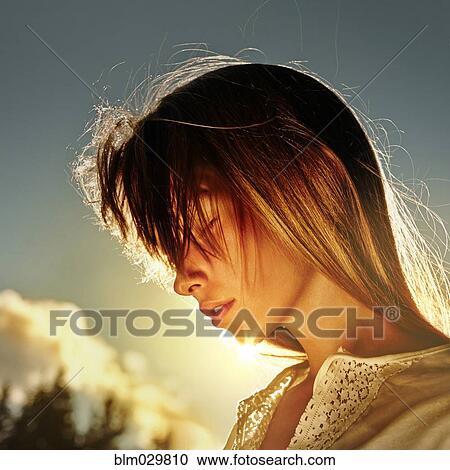 Stock Image - Caucasian girl standing in sun outdoors. Fotosearch