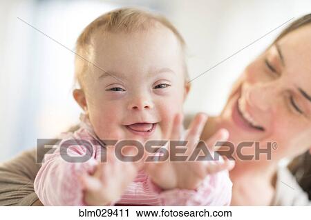 Stock Image - Caucasian mother playing with baby girl with Down Syndrome. Fotosearch