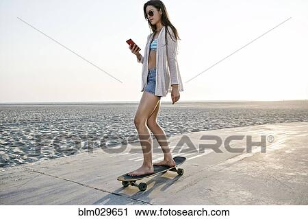 Stock Image - Caucasian woman skating on beach. Fotosearch