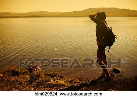 Caucasian woman standing by still rural lake View Large Photo Image Picture - Caucasian woman standing by still rural lake. Fotosearch