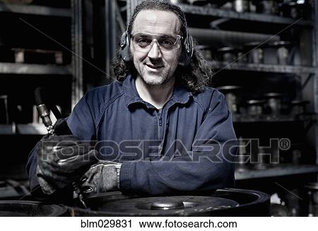 Stock Image - Caucasian worker operating machinery in factory. Fotosearch
