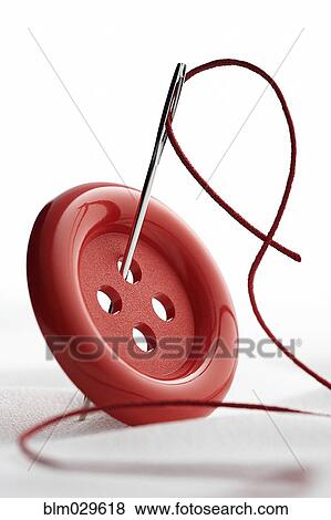 Stock Photo - Close up of needle and thread through button. Fotosearch