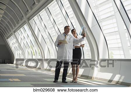 Stock Photo - Doctor and businesswoman talking in corridor. Fotosearch