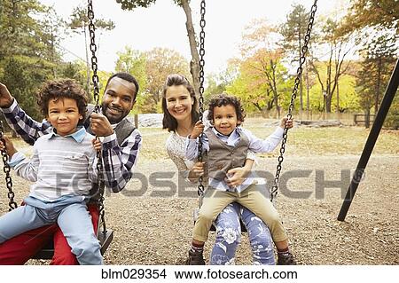 Family sitting on swings in park View Large Photo Image Picture - Family sitting on swings in park. Fotosearch