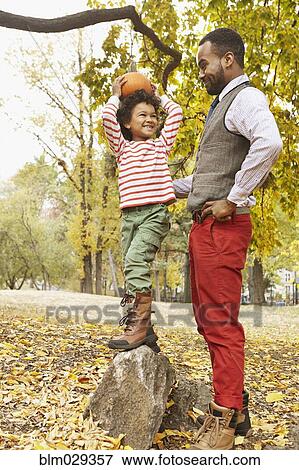 Stock Photo - Father and son holding pumpkin in park. Fotosearch