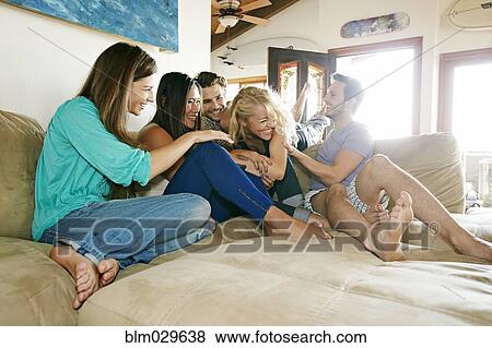 Friends relaxing together on sofa View Large Photo Image Stock Photo - Friends relaxing together on sofa. Fotosearch