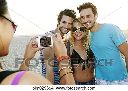 Friends taking pictures together on beach View Large Photo Image Picture - Friends taking pictures together on beach. Fotosearch