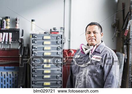 Stock Image - Hispanic mechanic standing in auto shop. Fotosearch