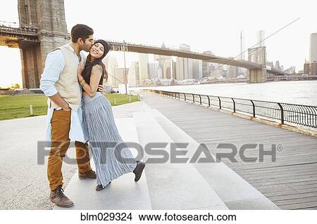 Picture - Indian couple kissing by bridge, New York, New York, United States. Fotosearch