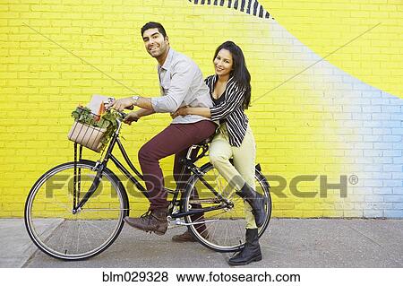Indian couple riding bicycle on city street View Large Photo Image Stock Photo - Indian couple riding bicycle on city street. Fotosearch