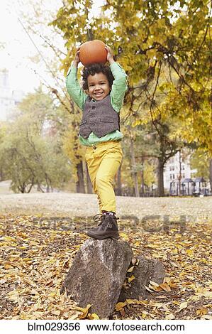 Mixed race boy holding pumpkin overhead in park View Large Photo Image Stock Photograph - Mixed race boy holding pumpkin overhead in park. Fotosearch