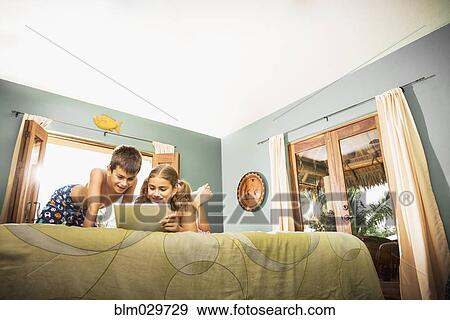 Mixed race children using digital tablet on bed View Large Photo Image Stock Photo - Mixed race children using digital tablet on bed. Fotosearch