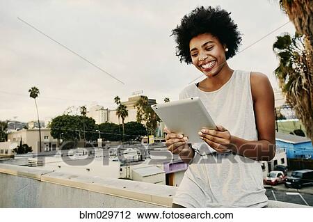 Mixed race woman using digital tablet on urban rooftop View Large Photo Image Stock Image - Mixed race woman using digital tablet on urban rooftop. Fotosearch