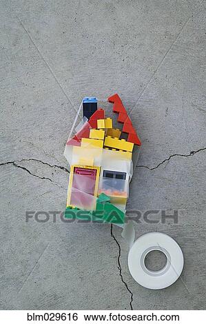 Stock Photograph - Plastic block house taped together on concrete. Fotosearch
