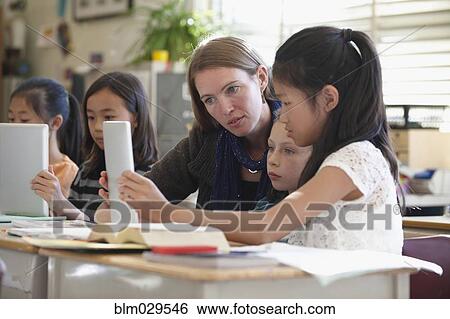 Stock Photograph - Students and teacher using digital tablets in class. Fotosearch