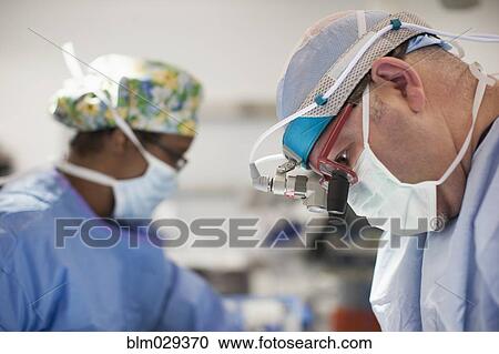 Surgeon wearing magnifying glasses in operating room View Large Photo Image Stock Image - Surgeon wearing magnifying glasses in operating room. Fotosearch