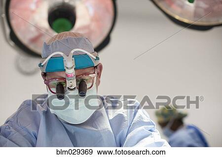 Surgeon wearing magnifying glasses in operating room View Large Photo Image Stock Photo - Surgeon wearing magnifying glasses in operating room. Fotosearch