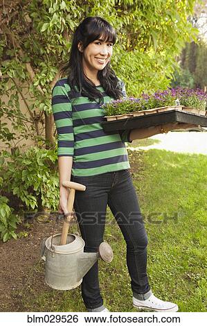 Stock Photograph - Woman carrying flower starts in backyard. Fotosearch