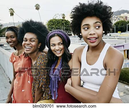 Stock Image - Women smiling on urban rooftop. Fotosearch