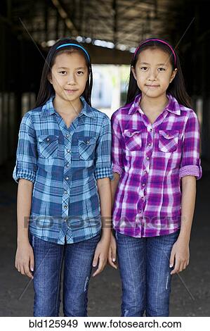 Stock Photo - Asian twin girls smiling in barn. Fotosearch